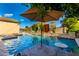 Beautiful pool featuring a water feature, umbrella, stone accents and blue water for outdoor entertaining at 5424 N 186Th Dr, Litchfield Park, AZ 85340