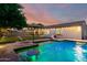 Sparkling pool with integrated lounge areas, surrounded by lush green grass and a covered patio for outdoor enjoyment at 5424 N 186Th Dr, Litchfield Park, AZ 85340
