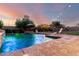 Outdoor pool with ambient lighting, a relaxing lounge area and lush greenery at 5424 N 186Th Dr, Litchfield Park, AZ 85340