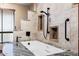 Luxurious soaking tub with shower head surrounded by tile walls and granite counter tops at 5536 N Camelback Canyon Pl, Phoenix, AZ 85018