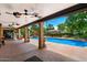 The covered patio, equipped with ceiling fans, provides a shaded spot to enjoy the pool and landscaping at 5536 N Camelback Canyon Pl, Phoenix, AZ 85018