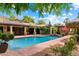 The sparkling pool is surrounded by lush landscaping, mature trees, and shaded seating areas for relaxation at 5536 N Camelback Canyon Pl, Phoenix, AZ 85018