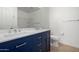 Bathroom featuring double sinks with blue vanity, quartz countertops, and tiled flooring at 7516 S 31St Pl, Phoenix, AZ 85042