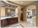 Luxurious bathroom with travertine floors, dark wood cabinetry, and a separate make up vanity at 10092 E Troon North Dr, Scottsdale, AZ 85262