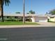 Inviting home featuring a well-maintained lawn, complemented by mature trees, and a convenient two-car garage at 10229 W Bolivar Dr, Sun City, AZ 85351
