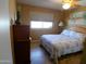 Cozy bedroom with a floral bedspread, wooden dresser, and a window with natural light at 11415 N 110Th Dr, Sun City, AZ 85351
