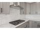 Close-up of a modern gas cooktop with stainless steel vent hood and gray cabinets with white backsplash at 13551 W Calle De Baca --, Peoria, AZ 85383