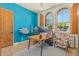 Home office featuring a modern desk, arched windows, and bright blue accent wall at 2011 W Calle De Las Estrella --, Phoenix, AZ 85085