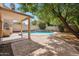 Relaxing backyard featuring a pool with a waterfall, covered patio, and mature trees at 2323 W Hunter Ct, Phoenix, AZ 85085