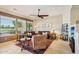 Comfortable living room featuring tile floors, leather furniture, and golf course views at 27320 N 127Th Dr, Peoria, AZ 85383