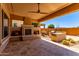 Outdoor patio with a stone fireplace, ceiling fan, desert landscaping and travertine floor at 27537 W Yukon Dr, Buckeye, AZ 85396
