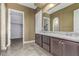 Bathroom featuring dual vanities with granite countertops, a framed mirror, and a doorway to a large walk-in closet at 27537 W Yukon Dr, Buckeye, AZ 85396