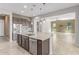 Open kitchen with stainless steel appliances, center island, and tile flooring flowing into the connected living room at 27537 W Yukon Dr, Buckeye, AZ 85396