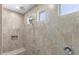 Modern walk-in shower with rainfall showerhead, a handheld shower, and decorative stone tile at 27537 W Yukon Dr, Buckeye, AZ 85396