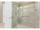 Glass-enclosed shower featuring neutral tile, grab bar, shower head, and glass door at 27537 W Yukon Dr, Buckeye, AZ 85396