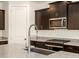 Modern kitchen with stainless steel appliances, dark cabinets, and a large sink at 37139 W Prado St, Maricopa, AZ 85138