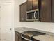 Modern kitchen with stainless steel appliances, dark cabinets, and stone countertops at 37139 W Prado St, Maricopa, AZ 85138