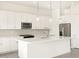 Modern kitchen features stainless steel appliances, white cabinetry, a center island, and stone backsplash at 37154 W La Paz St, Maricopa, AZ 85138