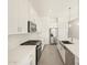 Modern white kitchen features stainless steel appliances, white cabinets and countertops, and neutral tile flooring at 37154 W La Paz St, Maricopa, AZ 85138