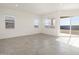 Well-lit living room with tiled flooring, large windows, and a sliding glass door leading to the patio at 37154 W La Paz St, Maricopa, AZ 85138
