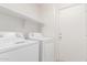 Clean laundry room with white washer and dryer, featuring overhead shelving for extra storage at 3728 W Fremont Rd, Phoenix, AZ 85041