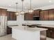 Modern kitchen featuring dark wood cabinets, stainless steel appliances, and a white center island with light countertops at 37385 W San Sisto Ave, Maricopa, AZ 85138