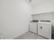 Clean laundry room with modern washer and dryer, a built-in shelf, and neutral tile flooring at 37399 W San Sisto Ave, Maricopa, AZ 85138