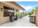 Covered back patio with a modern grill, outdoor dining set, and a tranquil view of the lush backyard at 528 E Kyle Ct, Gilbert, AZ 85296