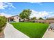 Large backyard featuring manicured artificial turf, mature landscaping, and a stone walkway leading to the pool at 528 E Kyle Ct, Gilbert, AZ 85296