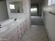 Bathroom featuring double sinks, cabinets, and neutral tiling at 6230 S Championship Dr, Chandler, AZ 85249