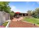 Charming backyard featuring a brick patio with an umbrella-covered table, surrounded by lush landscaping and mulch beds at 7611 E Pasadena Ave, Scottsdale, AZ 85250