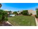 Spacious backyard with lush green grass, mature landscaping, a pool, and a shaded seating area at 7648 W Mauna Loa Ln, Peoria, AZ 85381