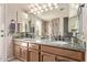 Double vanity bathroom with two mirrors, stone countertops, and natural light at 7648 W Mauna Loa Ln, Peoria, AZ 85381