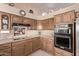 A cozy kitchen featuring wood cabinets and stone countertops with black and stainless steel appliances at 7648 W Mauna Loa Ln, Peoria, AZ 85381