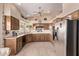 Open kitchen with stainless steel refrigerator, granite countertops, wooden cabinets, tile flooring, and recessed lighting at 7648 W Mauna Loa Ln, Peoria, AZ 85381