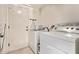 Bright laundry room with modern washer and dryer units, ironing board, and exterior door at 7648 W Mauna Loa Ln, Peoria, AZ 85381