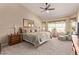 Cozy main bedroom with neutral tones, a ceiling fan, and a sitting area near a sunlit window at 7648 W Mauna Loa Ln, Peoria, AZ 85381