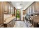 Well-lit laundry room with travertine floors, granite counters, wood cabinets, stainless washer and dryer, and access to the backyard at 8329 N Ridgeview Dr, Paradise Valley, AZ 85253