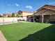 Well-manicured backyard with synthetic grass, a refreshing pool, and a covered patio at 9252 W Carol Ave, Peoria, AZ 85345