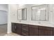 Bathroom featuring double sinks with dark wood cabinets, white countertops, and stylish mirrors at 1081 E Armstrong Way, Chandler, AZ 85286