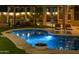 Serene backyard at night featuring a lit pool, cozy lounge area, and lush landscaping, creating a tranquil retreat at 10909 W Chase Ln, Avondale, AZ 85323