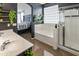 Modern bathroom featuring double sinks, soaking tub, glass-enclosed shower, and decorative shelving with plant accents at 10909 W Chase Ln, Avondale, AZ 85323