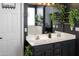 Chic bathroom features dual sinks, wood-look flooring, dark walls, and decorative plants at 10909 W Chase Ln, Avondale, AZ 85323