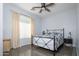 Light and airy bedroom with a metal frame bed, neutral curtains, ceiling fan, and wood-look flooring at 10909 W Chase Ln, Avondale, AZ 85323