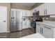 Bright kitchen features stainless steel appliances, white cabinets, mosaic backsplash, and wood flooring at 10909 W Chase Ln, Avondale, AZ 85323