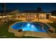 Stunning backyard at night featuring a glowing pool, covered patio with seating, and ambient lighting at 10909 W Chase Ln, Avondale, AZ 85323