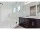 Modern bathroom with dual sink vanity, dark cabinets, and a glass-enclosed shower and tub at 12083 W Peak View Rd, Peoria, AZ 85383