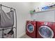 Functional laundry room with modern red washer and dryer, shelving, and ample space for sorting and folding at 12083 W Peak View Rd, Peoria, AZ 85383