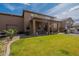 Backyard showing gravel landscaping, manicured lawn, outdoor kitchen, covered patio, and a two-story home at 12238 W Patrick Ct, Sun City, AZ 85373