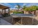 A trampoline sits in the backyard, surrounded by gravel landscaping, trees and a patio at 12238 W Patrick Ct, Sun City, AZ 85373